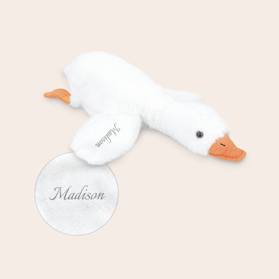 Personlig tilpasset gåsekosedyr Mykt, personlig kosedyr i form av en hvit gås, brodert med navnet "Madison" på vingen.