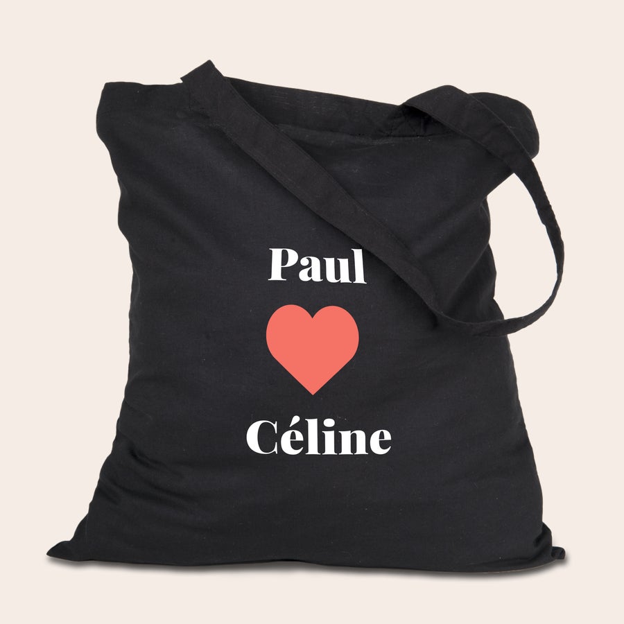 Tote bag personnalisé photo Tote bag personnalisé en coton bio noir avec Paul et Céline imprimés séparés par un cœur rouge