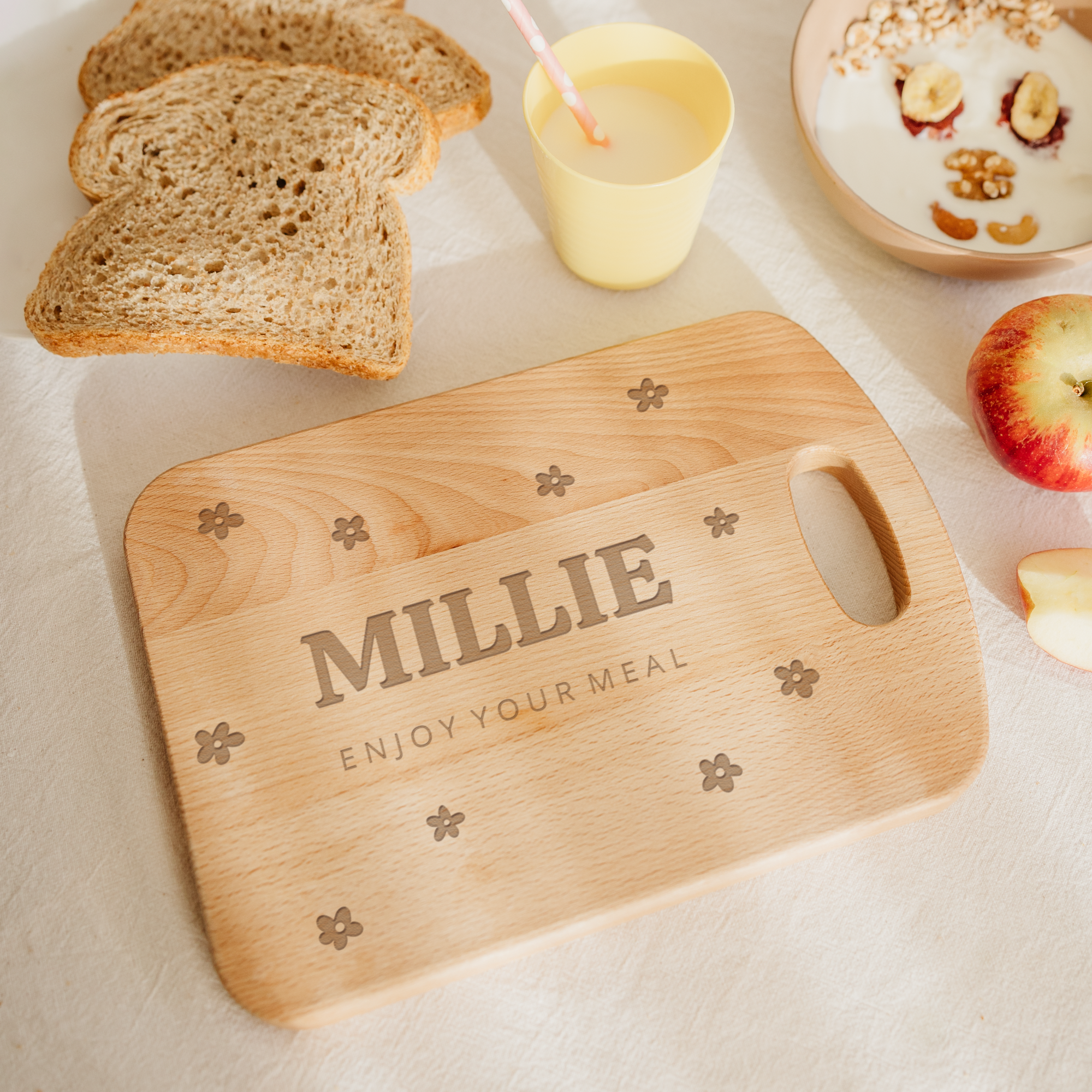 Tagliere in legno personalizzato inciso con il nome Millie e la frase Enjoy your meal circondato da fiori