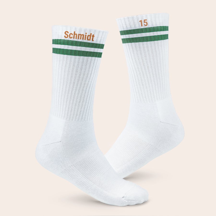 Sportsocken personalisieren Weißes Paar personalisierter Sportsocken mit grünen Streifen und aufgedrucktem Namen "Schmidt" und der Zahl "15"