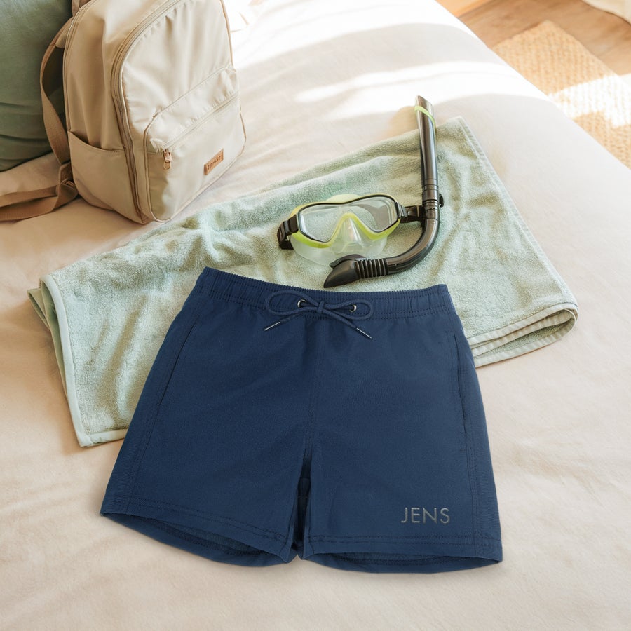 Personlige badeshorts Mørkeblå badeshorts med navnet Jens broderet på. Gør et plask med badeshorts broderet kun til ham.