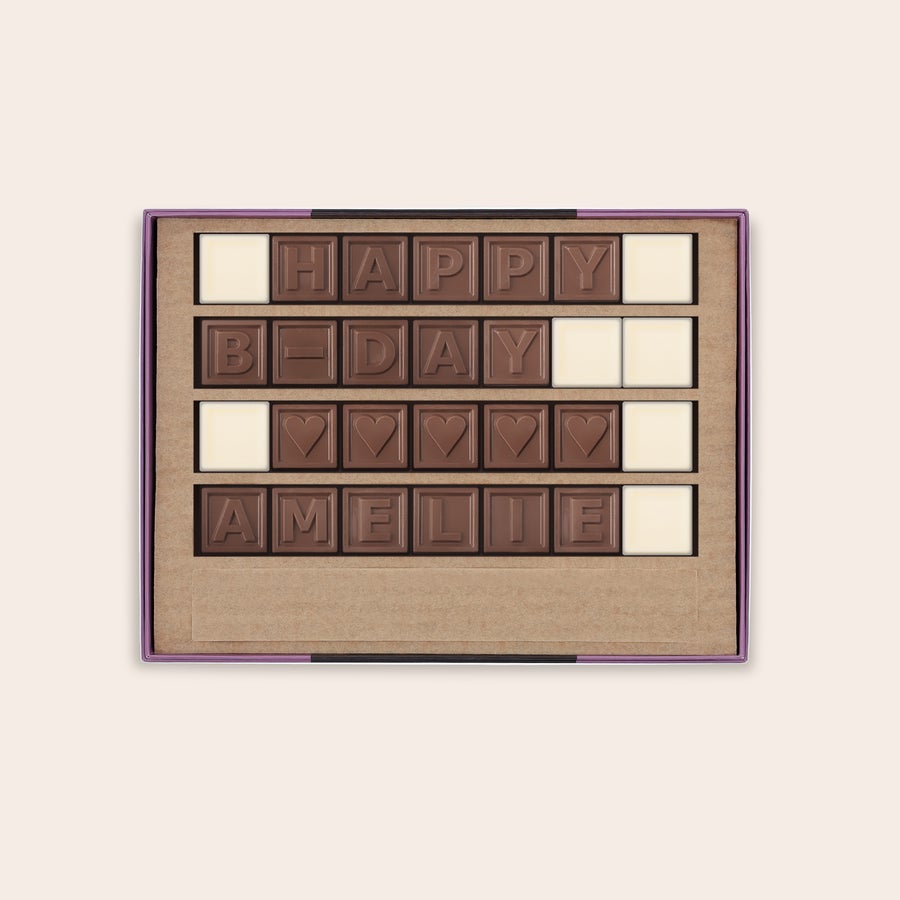 Schokotelegramm Selber Gestalten Personalisiertes Schokoladentelegramm mit der Nachricht "HAPPY B-DAY AMELIE" aus Milchschokoladenbuchstaben und Herzsymbolen sowie weißen Schokoladenstücken.