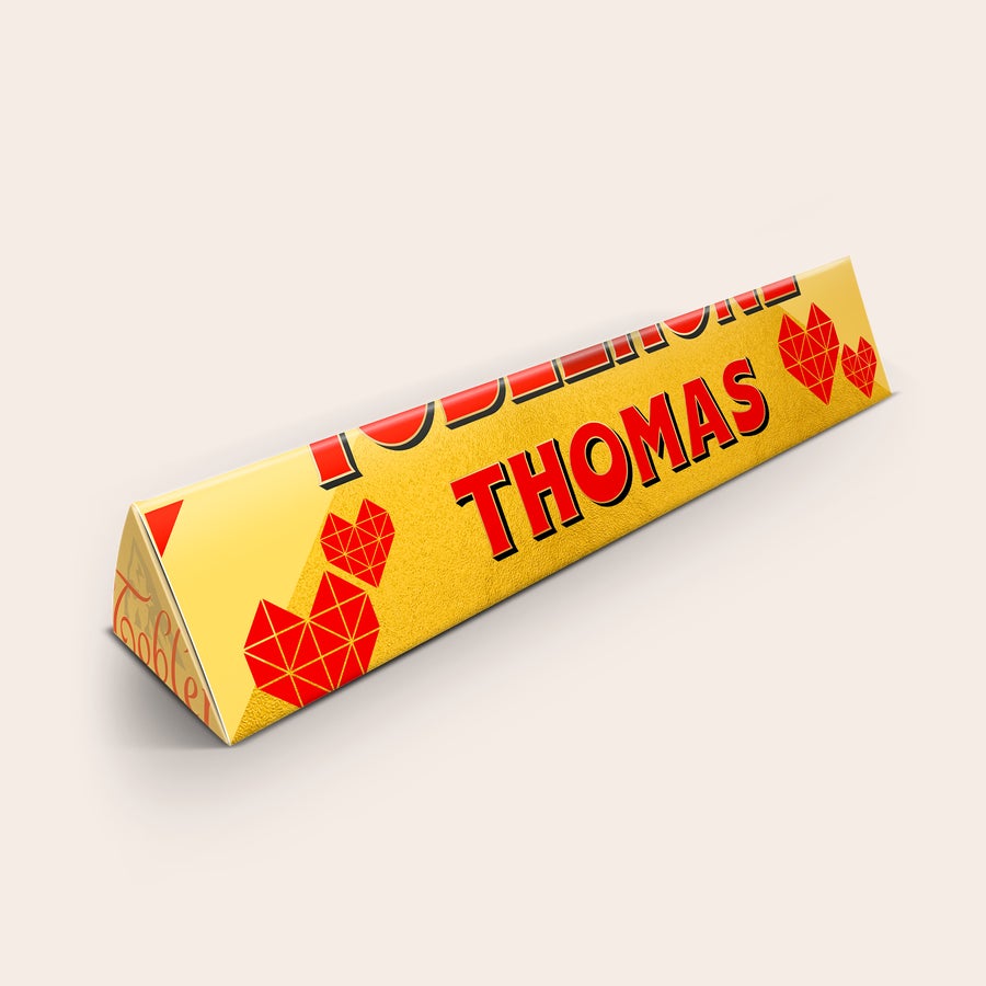 Toblerone personalizado - Amor Barra de chocolate Toblerone personalizada com o nome "THOMAS" e corações vermelhos, impressa na embalagem.