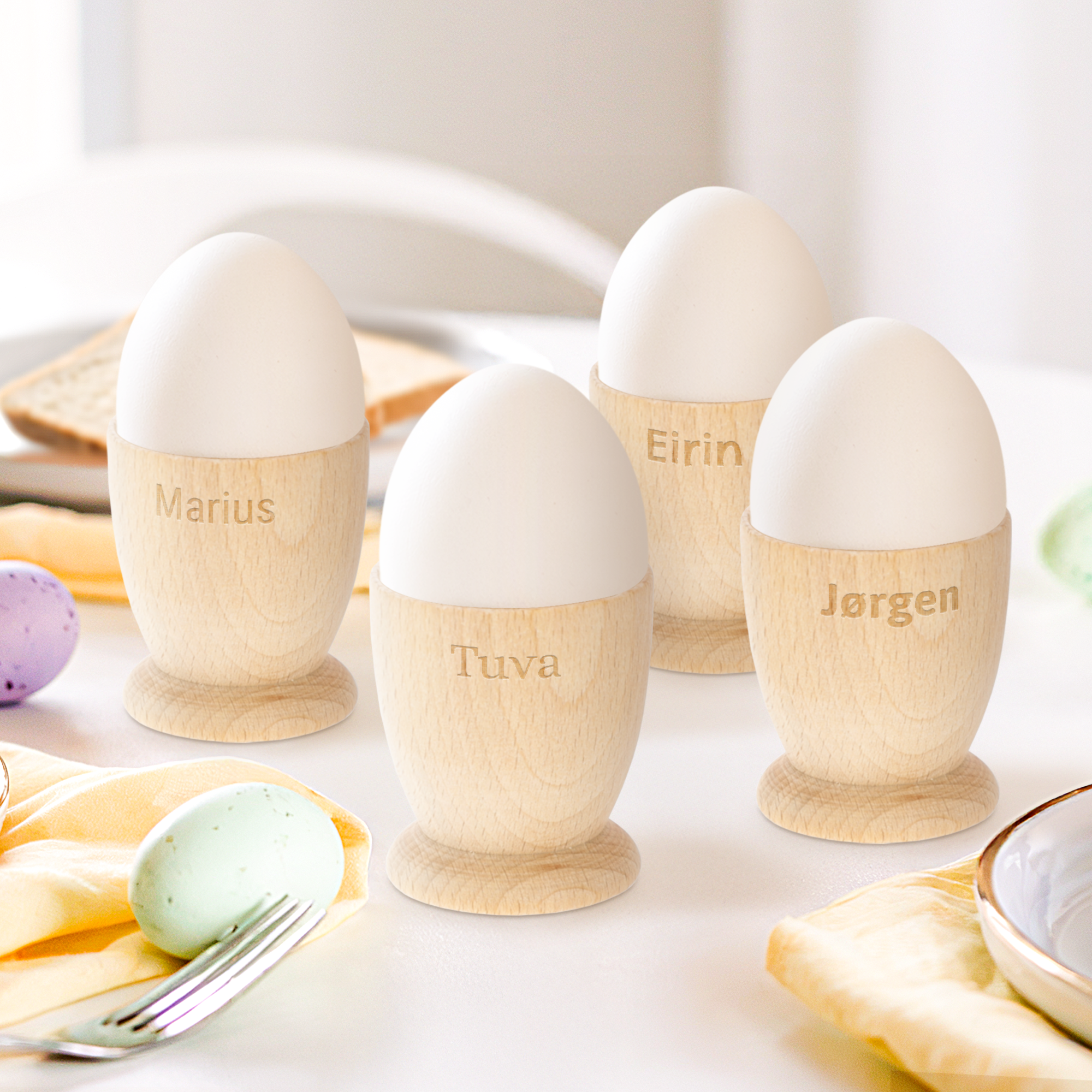 Personlige eggekopper i tre, gravert med navnene "Marius", "Tuva", "Eirin" og "Jørgen". Gjør frokosten minneverdig.