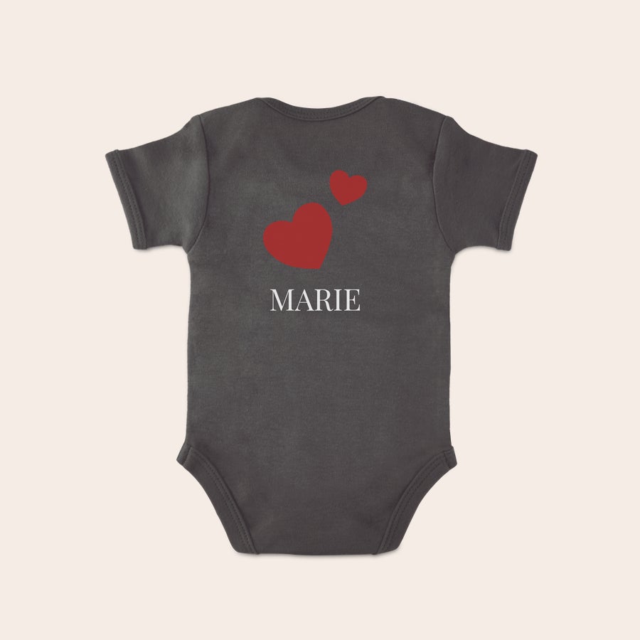 Baby Body bedrucken Grauer Babybody bedruckt mit dem Namen MARIE und zwei roten Herzen, um Eltern und Kind zu überraschen.