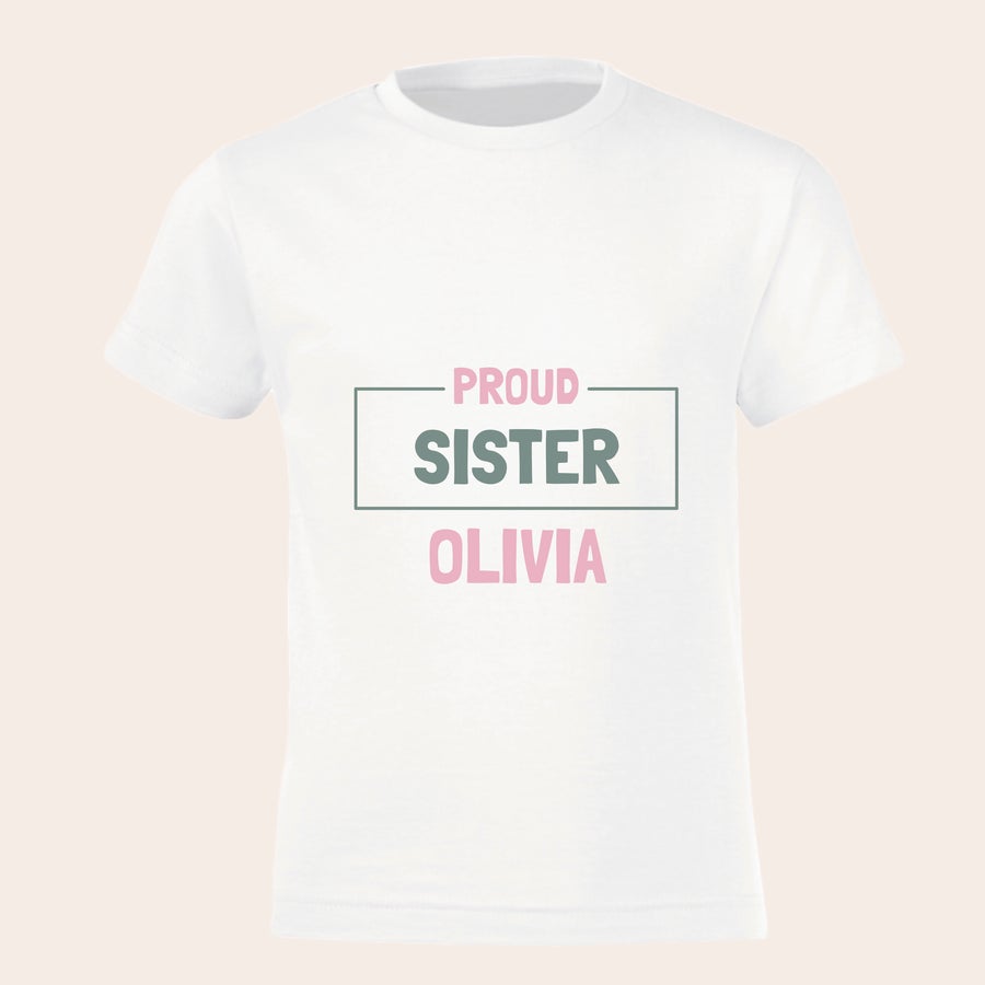 T-shirt Personalizada - Irmão/irmã mais velho/a T-shirt branca personalizada "Proud Sister Olivia" estampada com nome em cor-de-rosa.