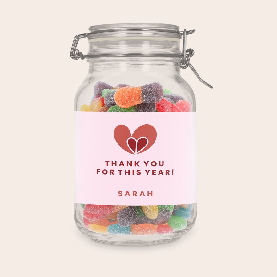 Személyre szabott édességes üveg Személyre szabott édes tégely savanyú pálcikákkal, rózsaszín címkével, szív grafikával és „THANK YOU FOR THIS YEAR! SARAH” szöveggel, nyomtatott díszítéssel.