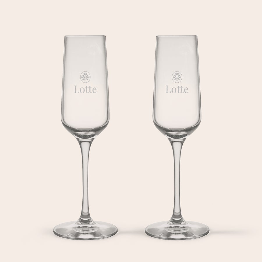 Champagneglas graveren Twee gepersonaliseerde kristallen champagneglazen, gegraveerd met de naam Lotte en een bloemenmotief.