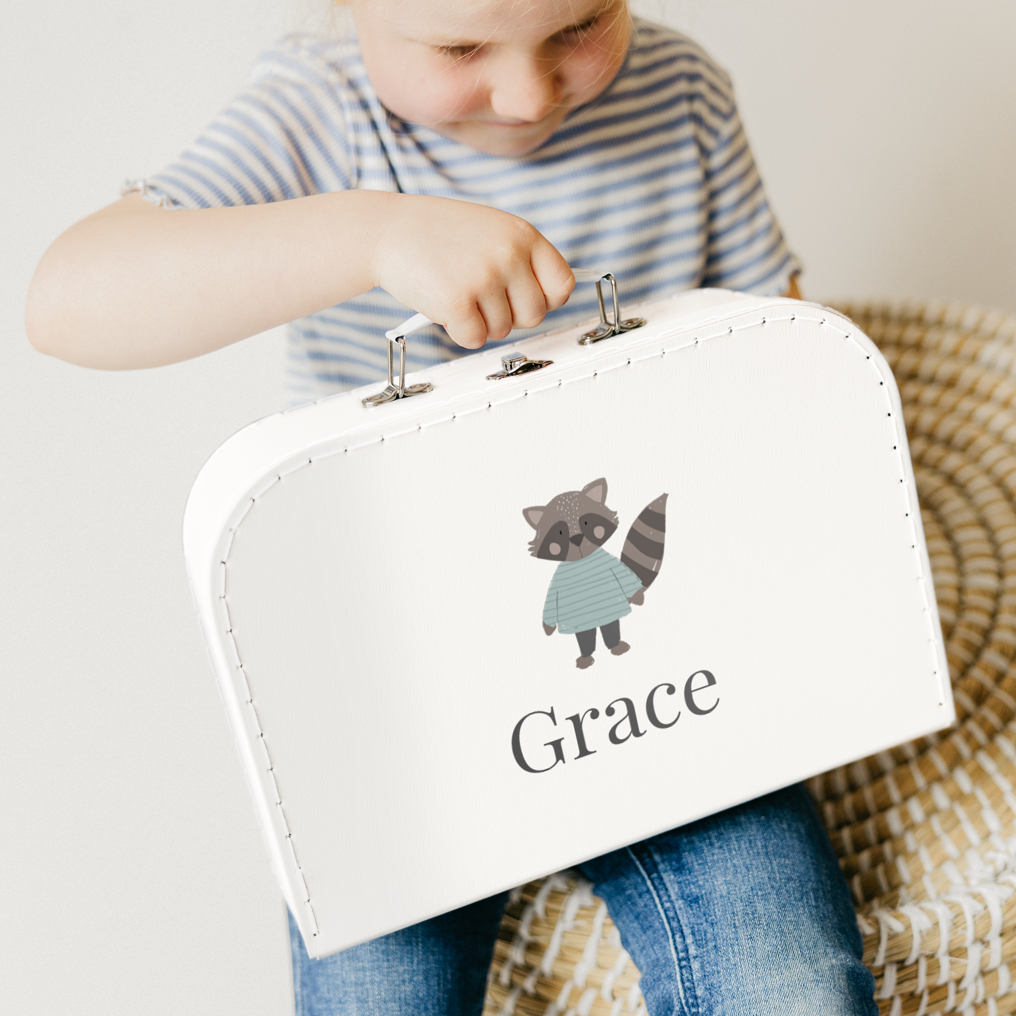 White toy suitcase printed with a raccoon design and the personalized name Grace, held by a child.