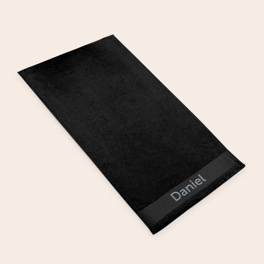 Bath towel with text Folded black bath towel embroidered with the name Daniel, a personalized black bath towel.