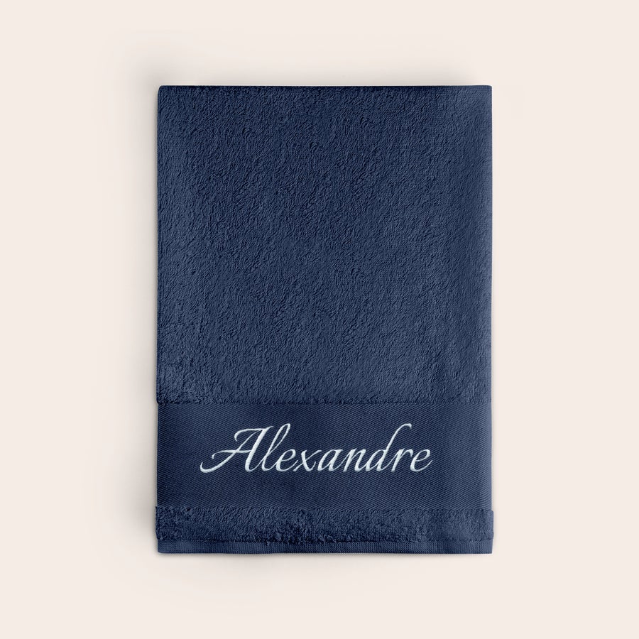 Toalha com texto Toalha azul marinho personalizada com o nome Alexandre bordado em branco.