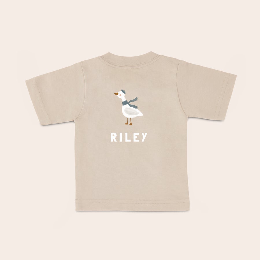 Baby T-shirt Personlig babyt-shirt i beige med en trykt gås med hue og tørklæde samt navnet RILEY