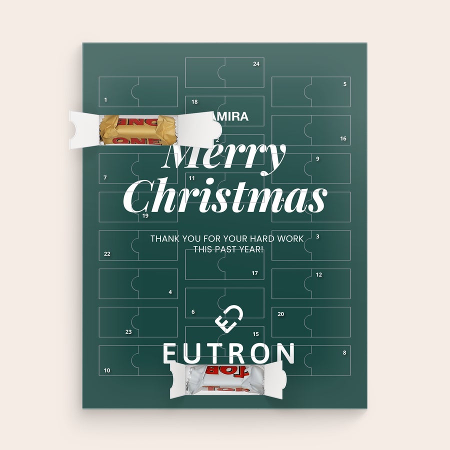Calendario dell'Avvento Personalizzato - Toblerone 2025 Calendario dell'avvento personalizzato verde petrolio stampato con il nome Amira, un messaggio e due cioccolatini Toblerone a vista.