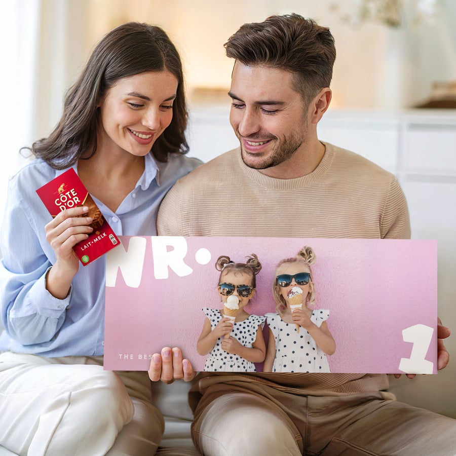 Tavoletta di Cioccolato Côte d'Or XL Personalizzata Una coppia tiene in mano una tavoletta di cioccolato XXL Côte d'Or personalizzata con la foto di due bambine e un messaggio stampato