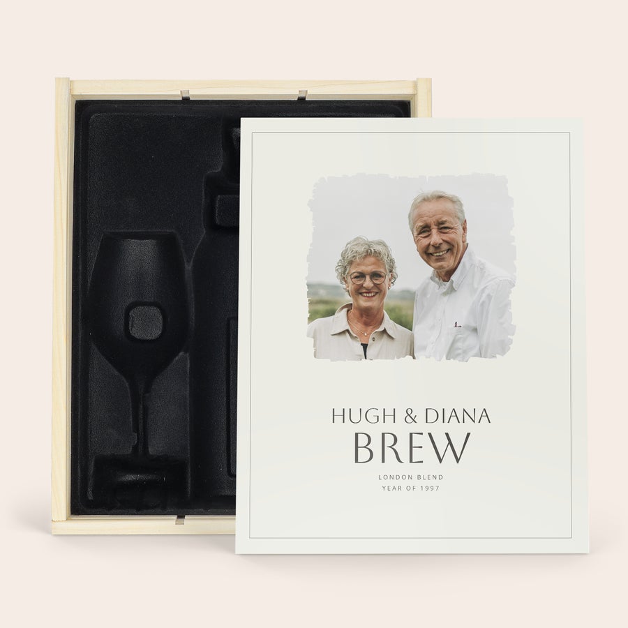 Henkilökohtainen puinen kotelo Deluxe-puinen kotelo mustalla sisustuksella, jossa on yksilöllinen painatus valokuvalla ja tekstillä "HUGH & DIANA BREW LONDON BLEND YEAR OF 1997" kannessa, tilaa pullolle ja 2 viinilasille.
