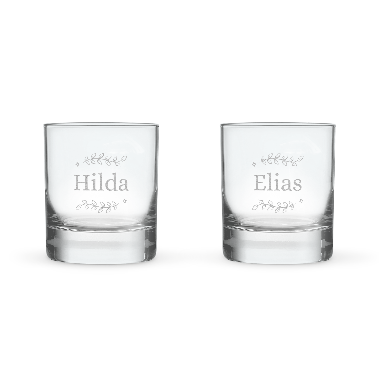 Två graverade tumblerglas, ett med namnet Hilda och det andra med Elias, omgivet av löv. Personligt graverat tumblerglas med namn eller text.