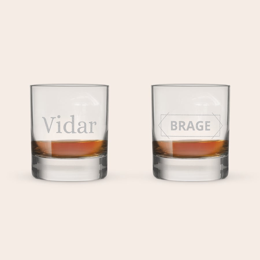 Brennevinsglass To brennevinsglass med "Vidar" og "BRAGE" gravert, fylt med ravfarget væske og isballer.