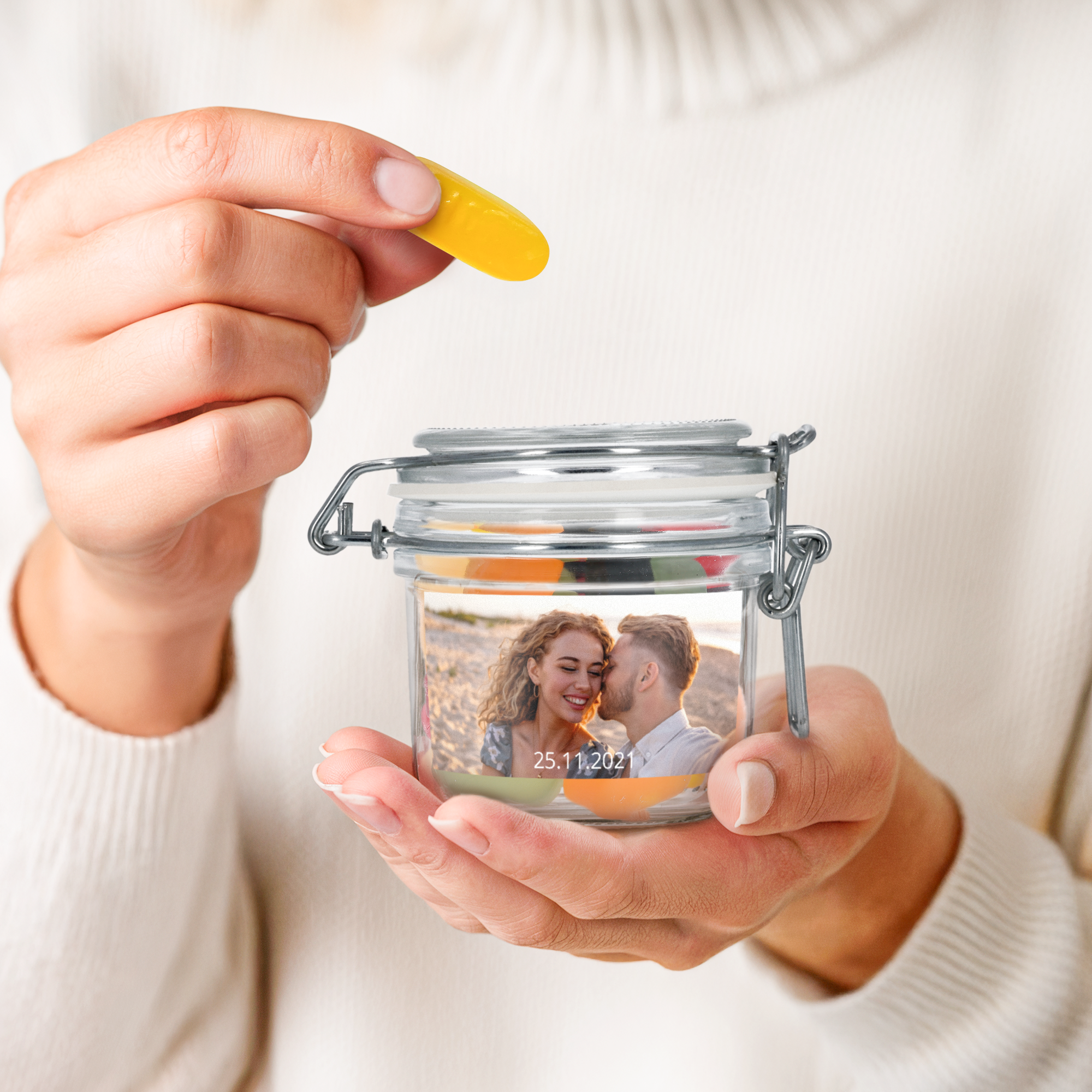 Hands holding a personalised sweet jar with winegums, printed with a photo of a couple and a date.