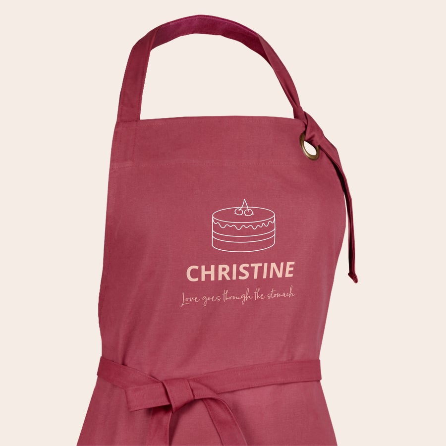 Grembiule Grembiule da cucina personalizzato color lampone con design stampato a forma di torta il nome Christine e la scritta Love goes through the stomach