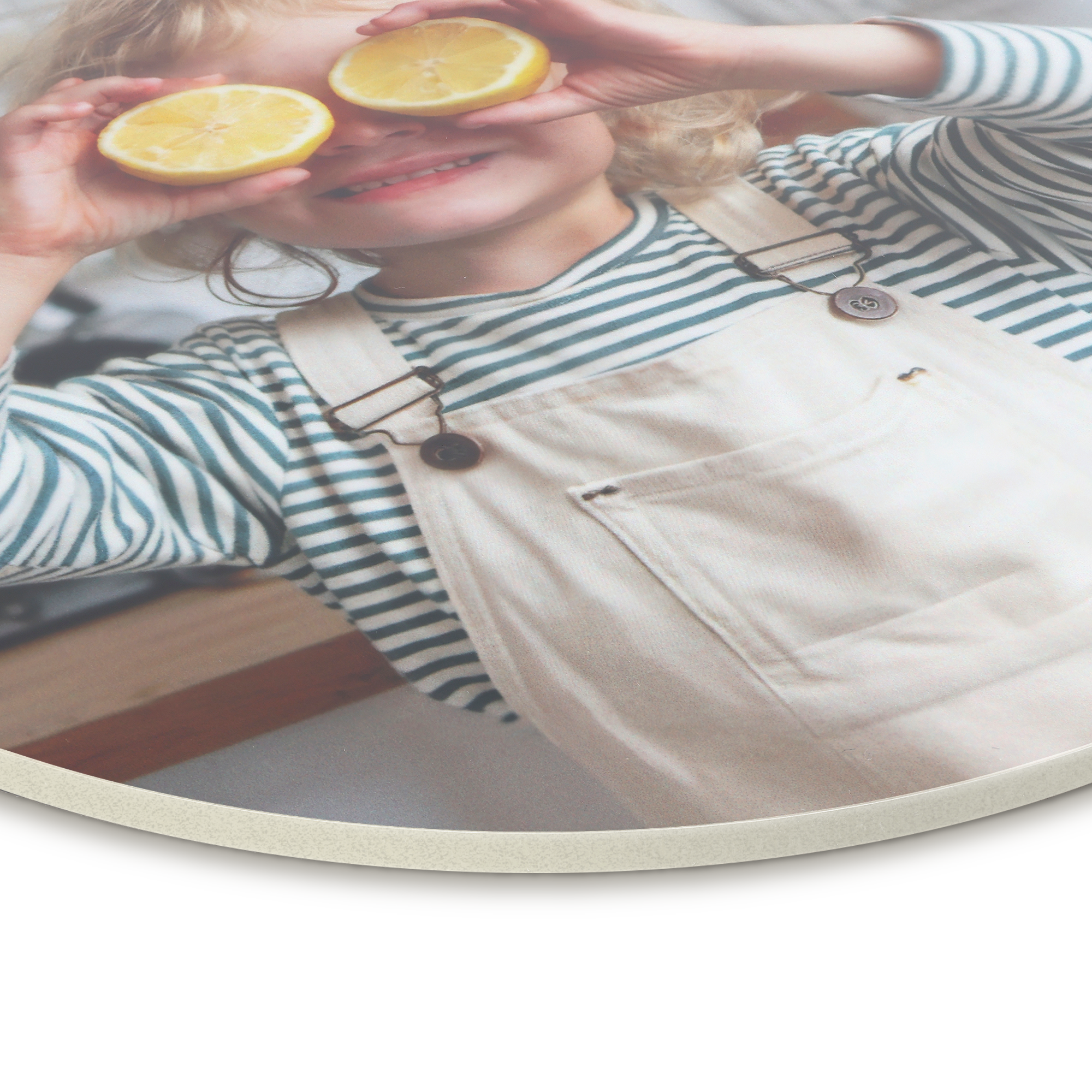 Round forex wall art panel featuring a smiling child holding lemon halves over their eyes, printed with a personalized photo.