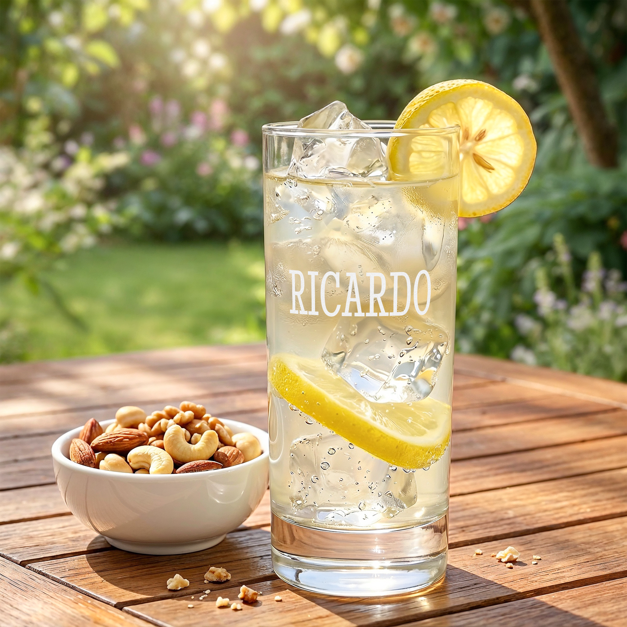 Gepersonaliseerd longdrinkglas graveren met de naam Ricardo, geserveerd met citroen en ijsblokjes op een houten tafel.