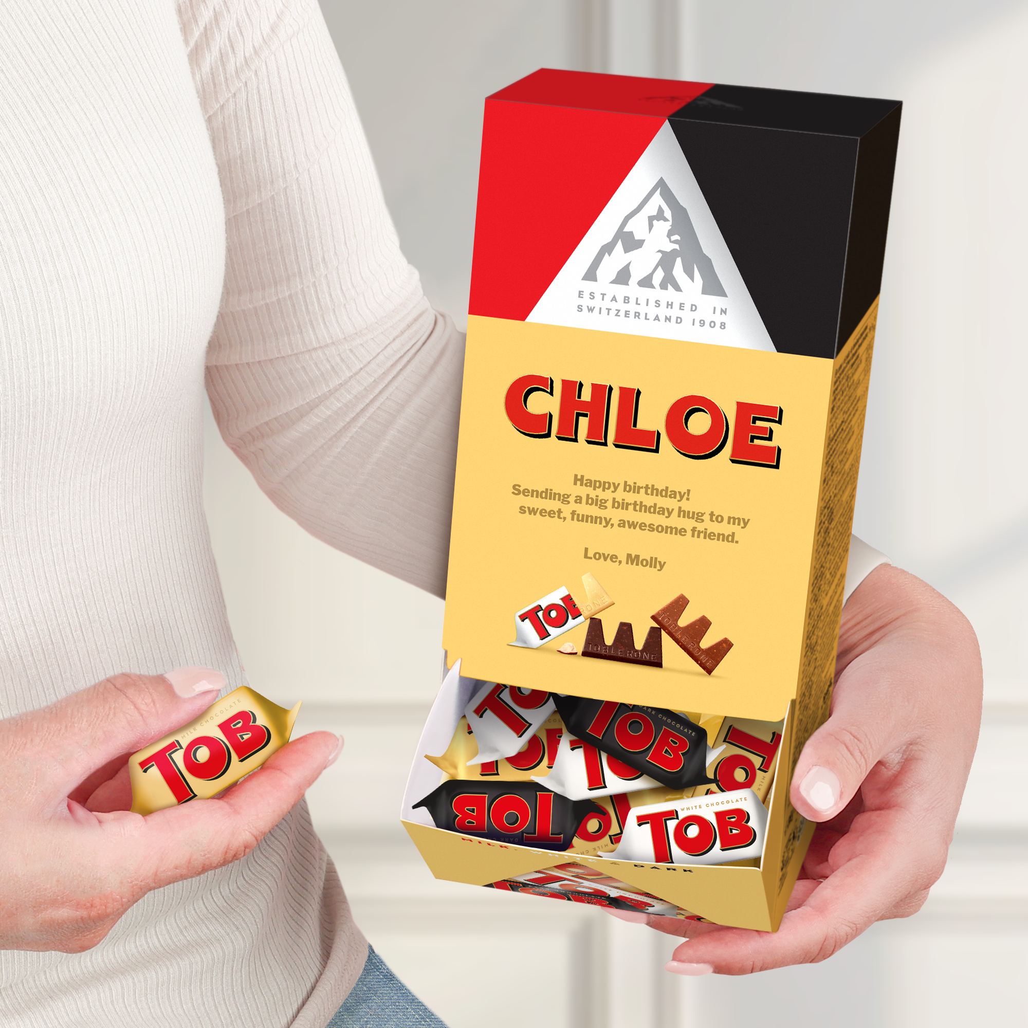 Dispensador de chocolate Toblerone personalizado com nome Chloe, mensagem de aniversário impressa e chocolates variados. Surpreenda-os com um dispensador de chocolate Toblerone personalizado.