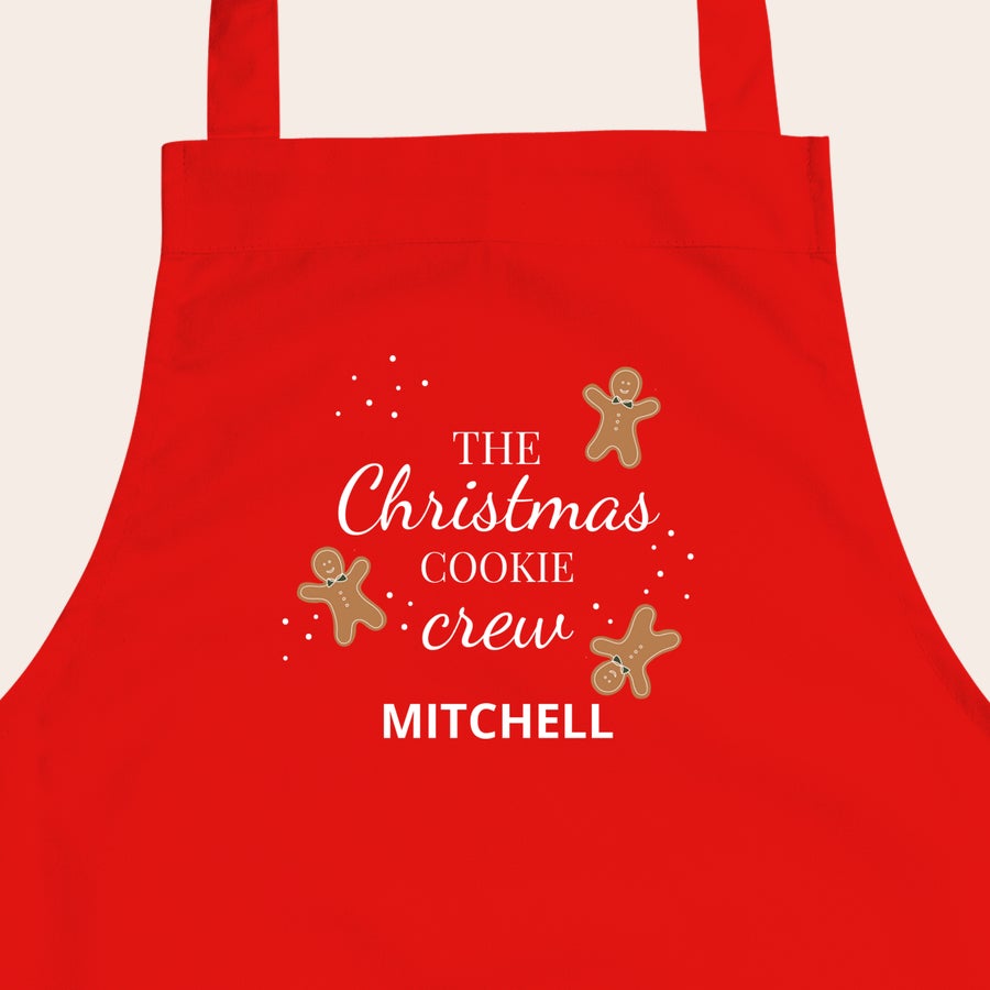 Grembiule per bambini Grembiule per bambini rosso con scritta "The Christmas Cookie Crew" e nome Mitchell, stampato con simpatici omini di pan di zenzero