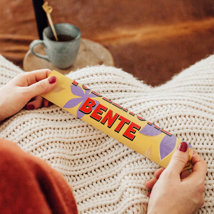 Personlig Toblerone - Morsdag Personlig Toblerone-sjokoladebar med navnet "BENTE" trykt på gul emballasje, holdt av hender.