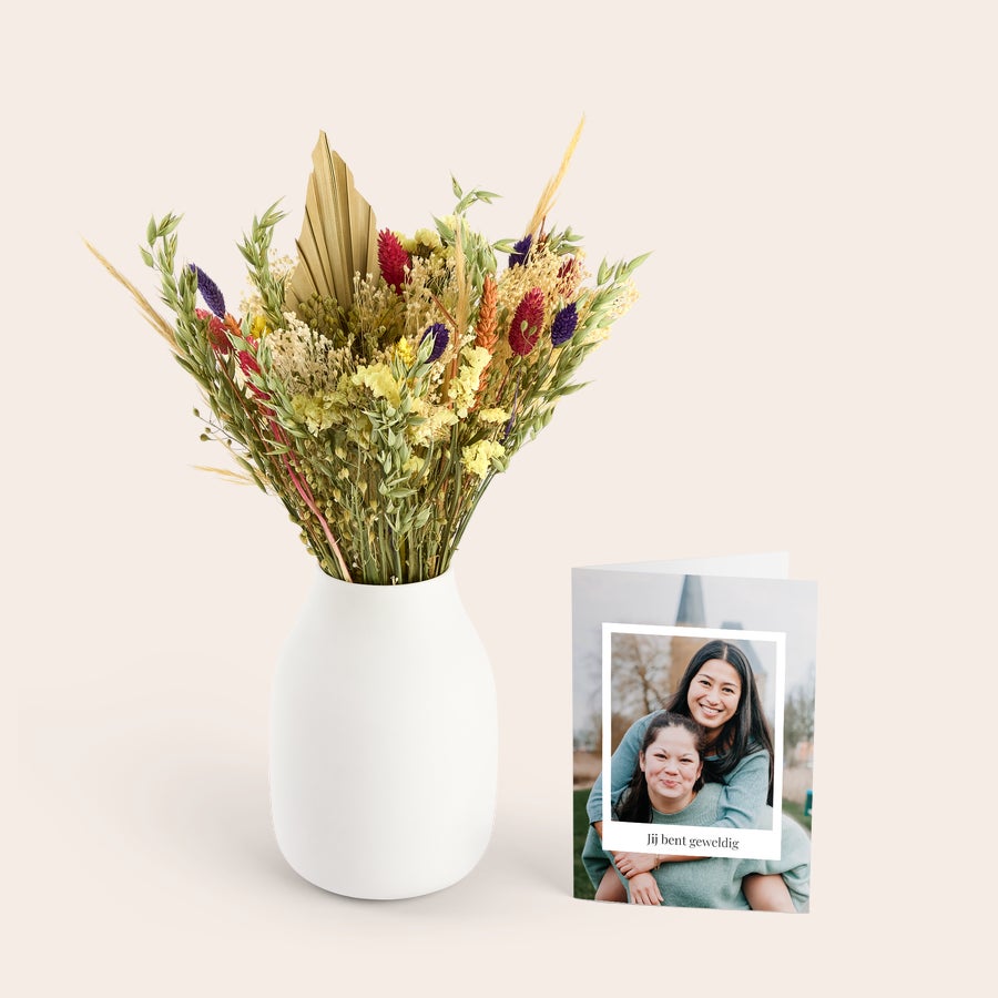 Ramo de flores secas con tarjeta recordatoria Ramo de flores secas de varios colores en jarrón blanco con tarjeta de felicitación personalizada con foto y texto.
