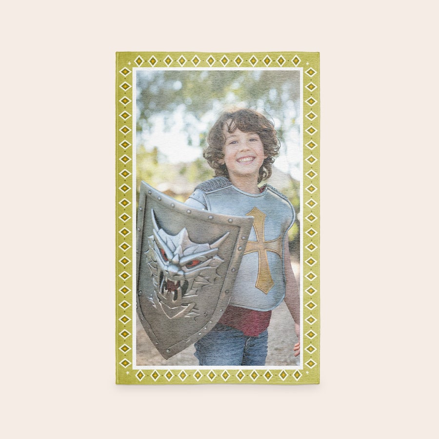Tapete de jogos impresso Tapete de brincar personalizado com uma foto impressa de uma criança sorridente vestida de cavaleiro, segurando um escudo, ideal para transformar a hora da brincadeira.