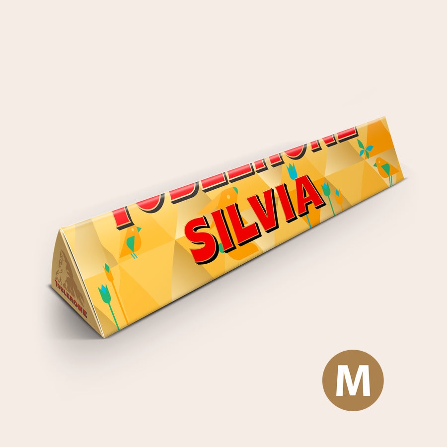 Toblerone Personalizzato - Pasqua Un delizioso Toblerone personalizzato con design pasquale stampa "SILVIA" e motivi a tema