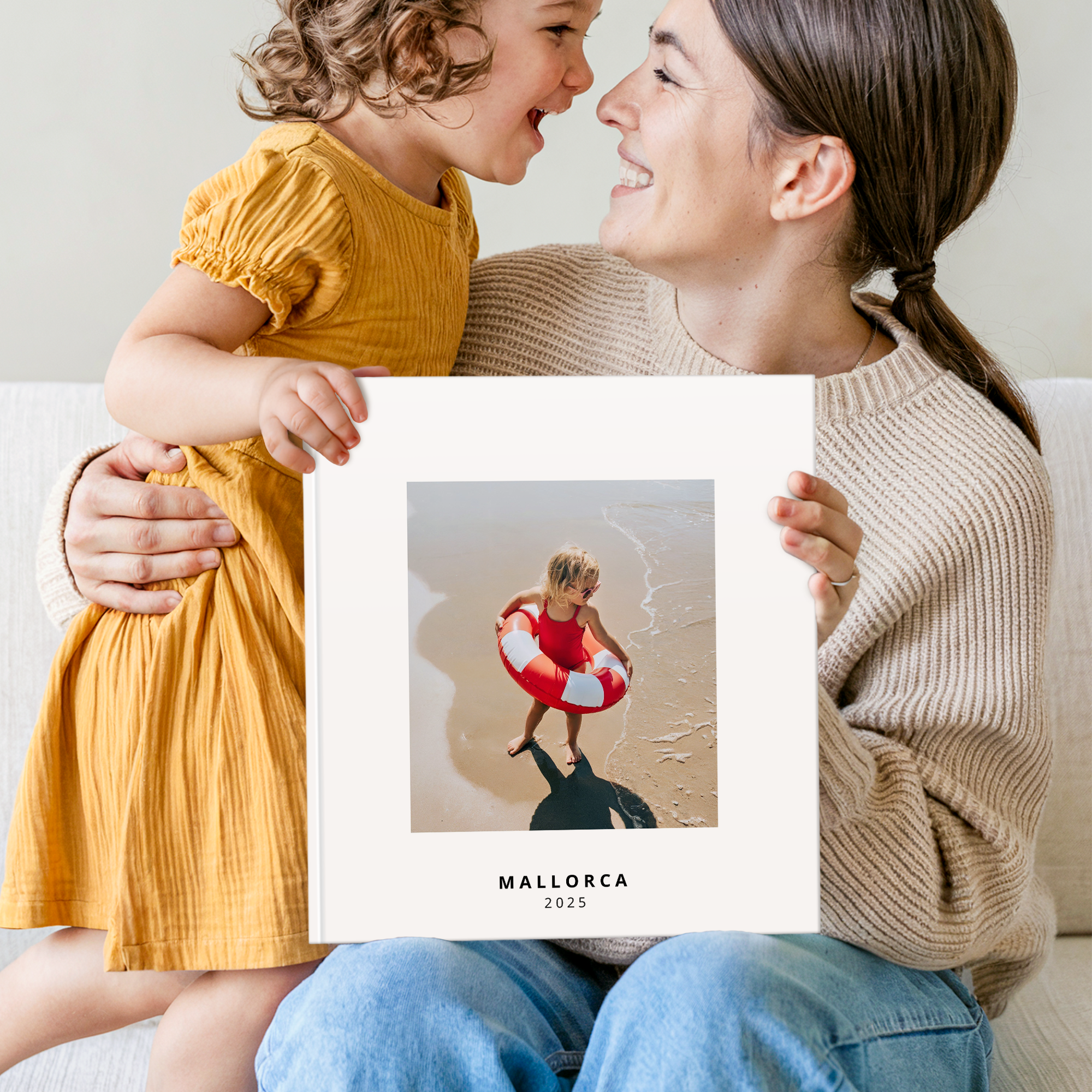 Mamma e figlia tengono un album fotografico personalizzato con una foto stampata e la scritta "MALLORCA 2025"