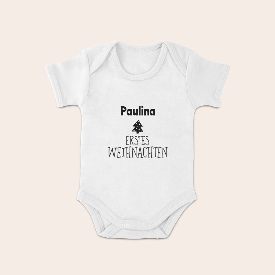 Weihnachtsbody Baby Weißer Baby Body mit personalisiertem Namen "Paulina" und dem Text "Erstes Weihnachten" unter einem Tannenbaum-Motiv, gedruckt mit tollen Weihnachtsdesigns