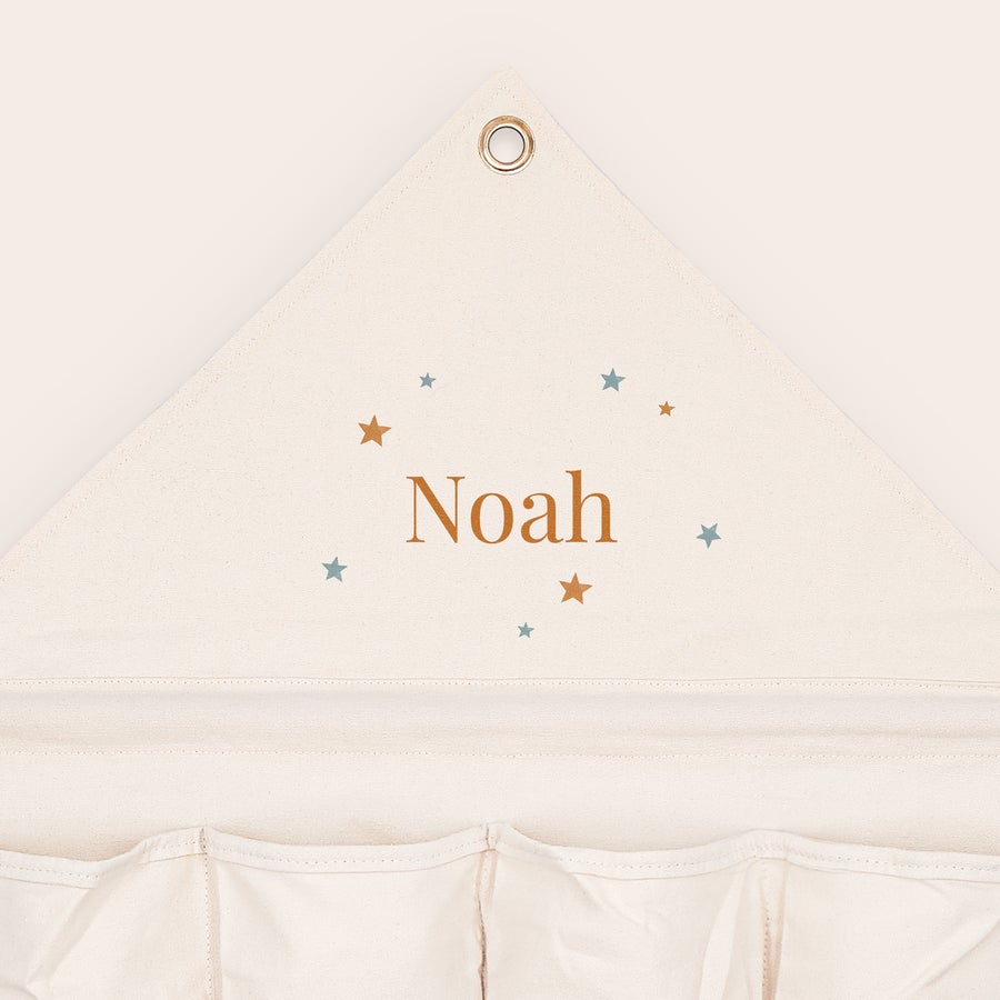 Organizer för fickor i tyg Personlig fickorganisator i tyg med namnet Noah och stjärnor tryckt på den krämfärgade tygfickorganisatorn.