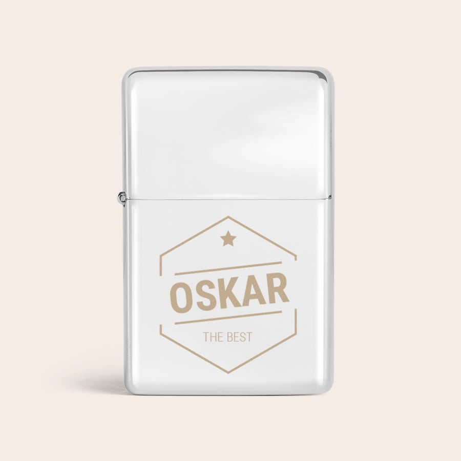 Graverade tändare En personlig silvertändare, graverad med namnet OSKAR i guldtoner tillsammans med texten THE BEST i en hexagonal ram med en stjärna högst upp.