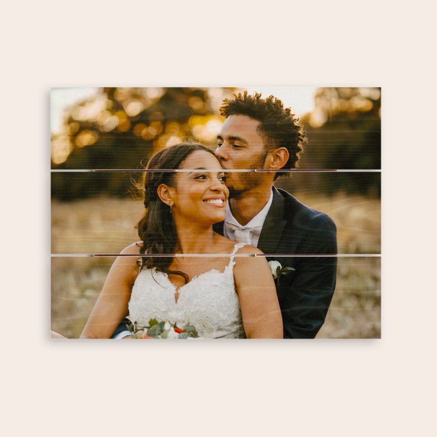 Photo on wood A personalized photo print on wooden planks showing a wedding couple embracing in a field with a natural, rustic look