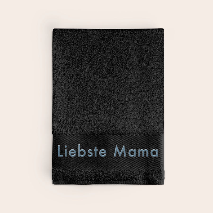 Badetuch mit Namen Personalisiertes schwarzes Badetuch mit dem Text „Liebste Mama“ in Hellblau bestickt. Erschaffe etwas Einzigartiges.