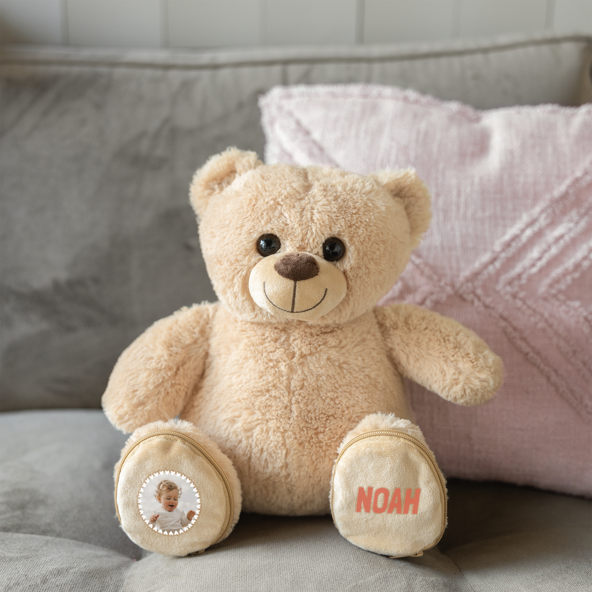 A personalized teddy bear with a printed photo of a baby on one foot and the name NOAH on the other foot