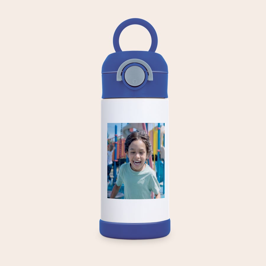 Sticlă de apă pentru copii cu fotografie Sticlă de apă personalizată pentru copii din oțel inoxidabil, albă cu bază albastră, capac albastru, mâner și un buton gri, imprimată cu fotografia unui băiat râzând.