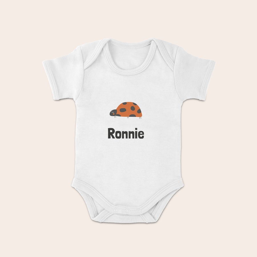 Baby body med tryk Hvid babybody med tryk af en mariehøne og navnet Ronnie. Lav din egen personlige baby body med tryk.