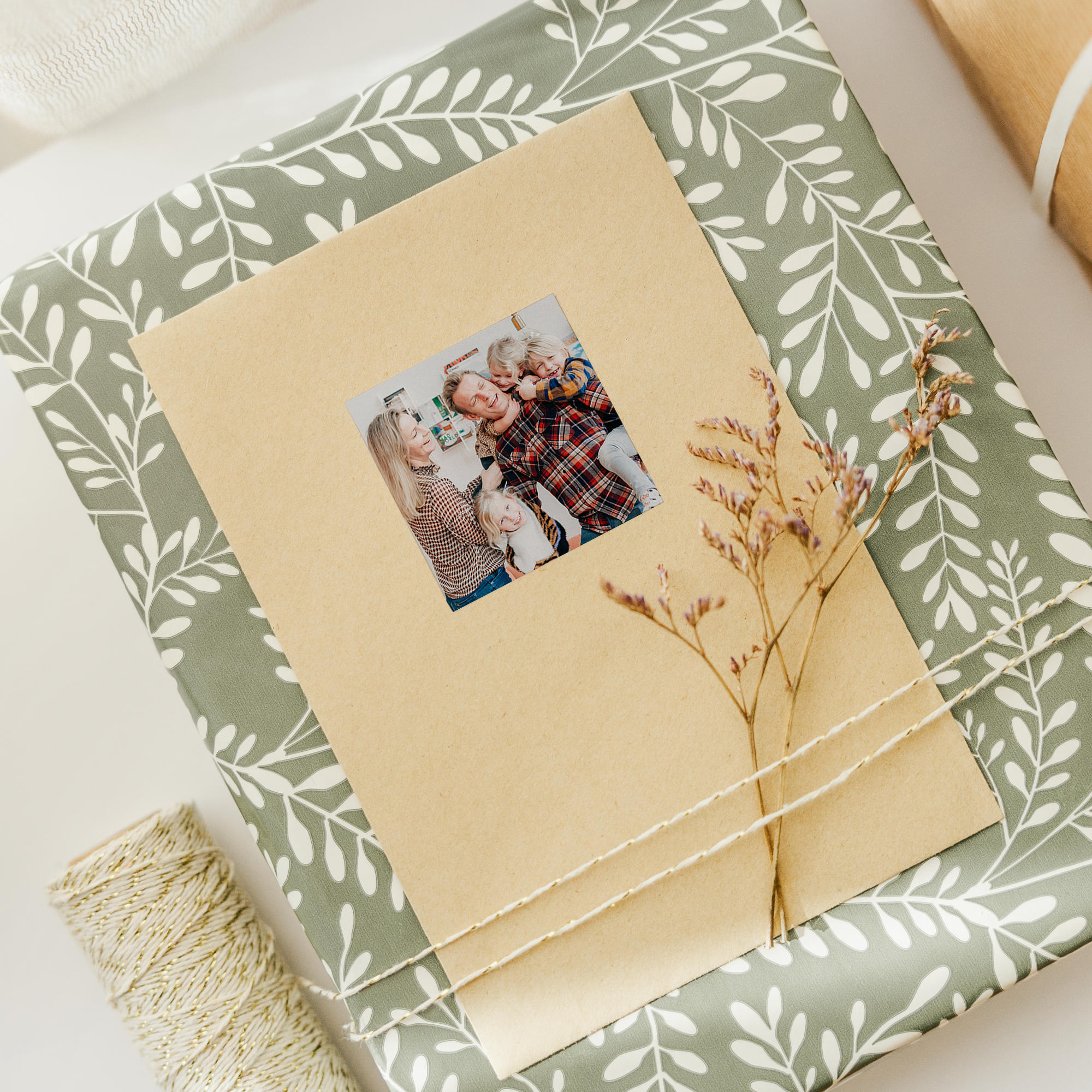 Pegatinas personalizadas con foto impresa de una familia sobre papel de regalo con hojas verdes.