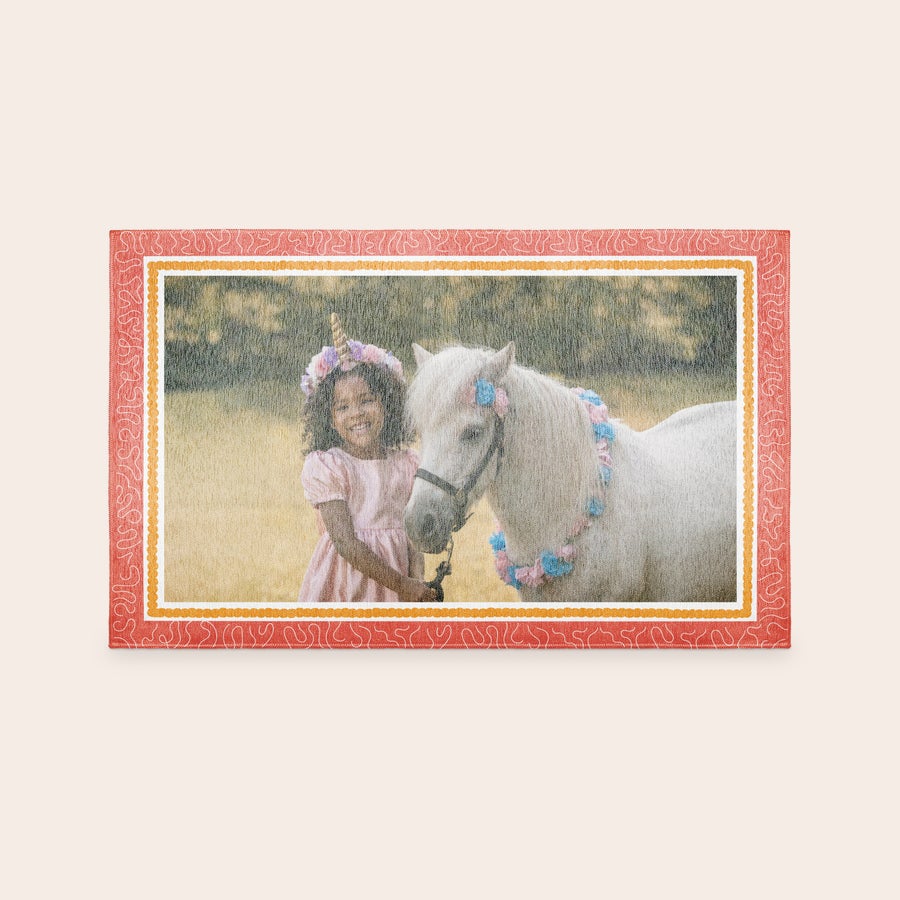Alfombra de juegos impresa Tapete de juego personalizado con foto impresa de una niña con un poni blanco con guirnaldas y un borde decorativo.