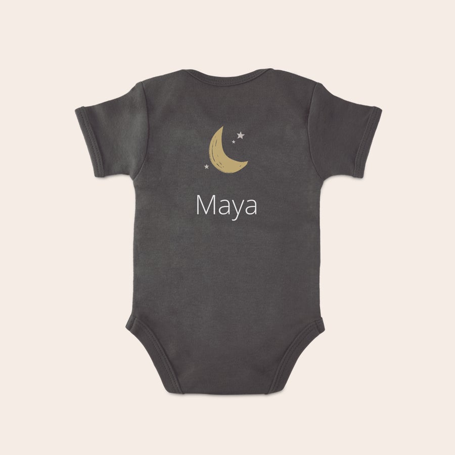 Body med eget tryck Mörkgrå body med eget tryck, en guldmåne, små stjärnor och namnet "Maya" tryckt i vitt.