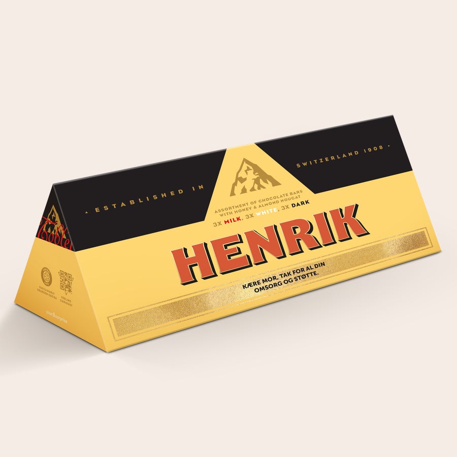 Toblerone med navn Denne personlige XL Toblerone Selection chokoladebar med navn "HENRIK" og teksten "KÆRE MOR, TAK FOR AL DIN OMSORG OG STØTTE" er en virkelig stor overraskelse. Trykt omslag med bjerglogo og teksten "ESTABLISHED IN SWITZERLAND 1908".