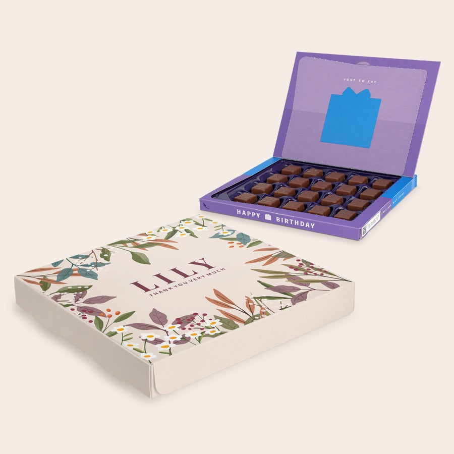 Povedz to s darčekovou krabičkou Milka - Ďakujem Personalizovaná darčeková krabička Milka s menom Lily a textom Thank you very much, vytlačená plnofarebne s kvetinovým motívom, otvorená krabička s nápisom Happy Birthday a čokoládovými pralinkami.