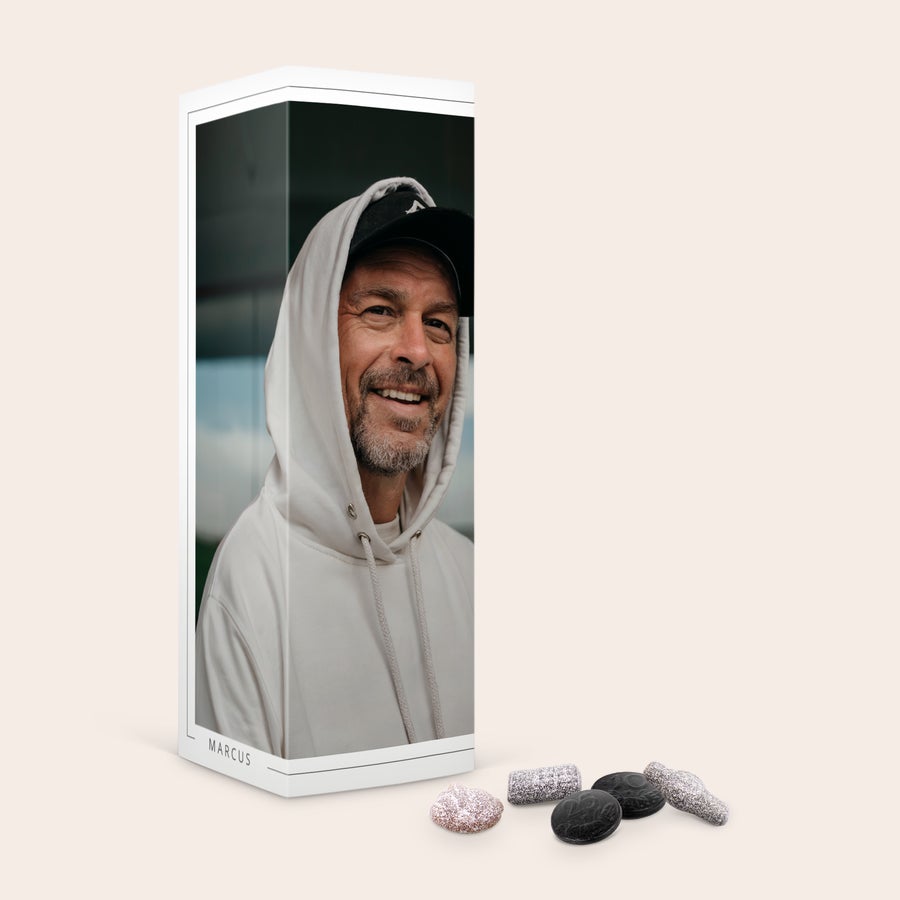 Personlig presentförpackning för godis En personlig lakritsask tryckt med foto av man och texten "MARCUS" med Klene lakritsgodisar vid sidan.
