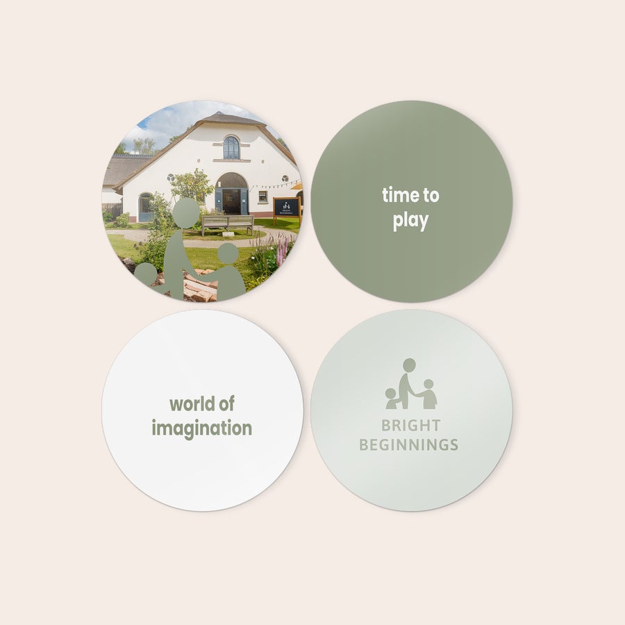 Personalised wall art panels Four round personalized wooden wall art panels, one printed with a building, one with "time to play" text, one with "world of imagination" text, and one with "BRIGHT BEGINNINGS" text and an image of an adult with two children.