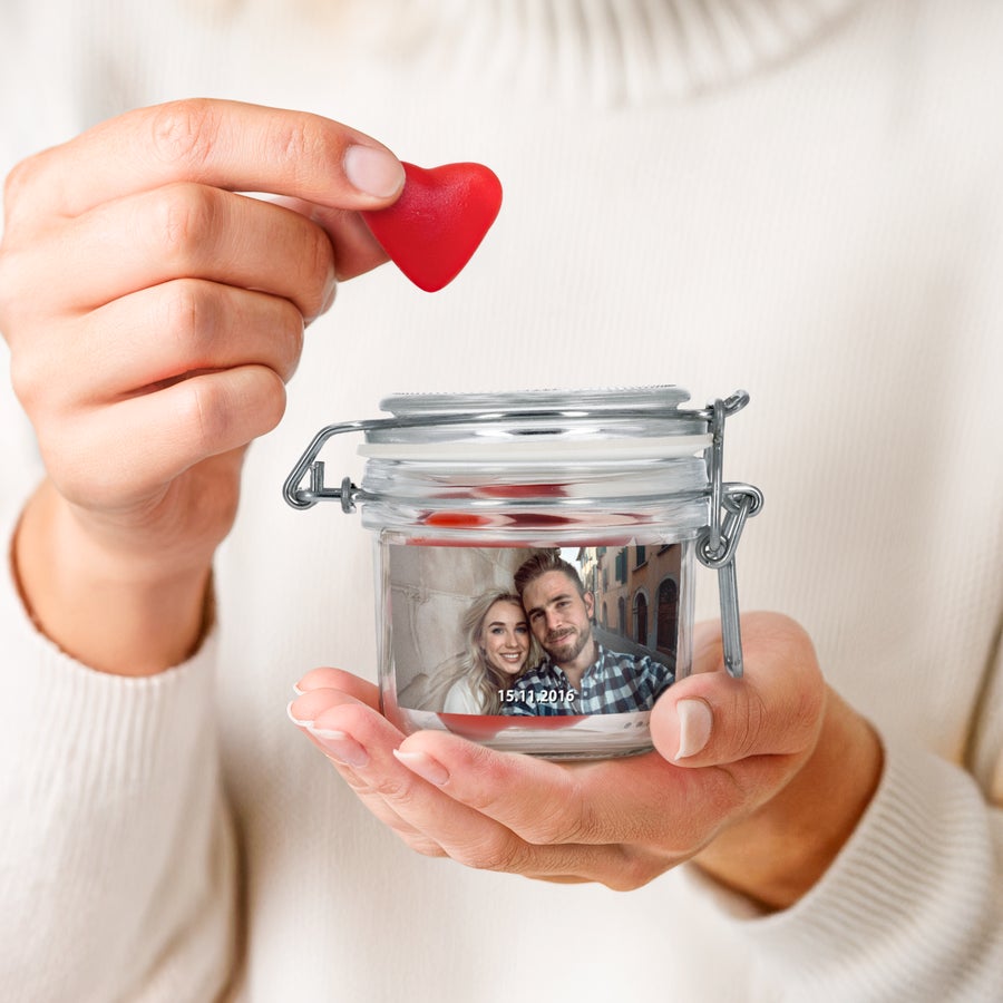 Borcan de dulciuri personalizat Borcan dulci personalizat cu inimioare, cu fotografia de cuplu si data imprimata, tinut in maini.