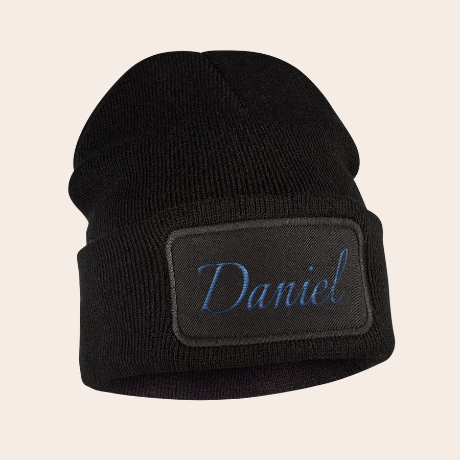 Hue med navn - Broderet Sort beanie med blåt broderet navn Daniel på en cool label holder ørerne varme med stil.