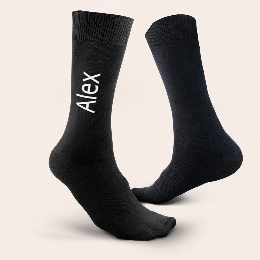 Calcetines con nombre Un par de calcetines negros personalizados con el nombre "Alex" estampado en blanco. Diseña los calcetines personalizados.